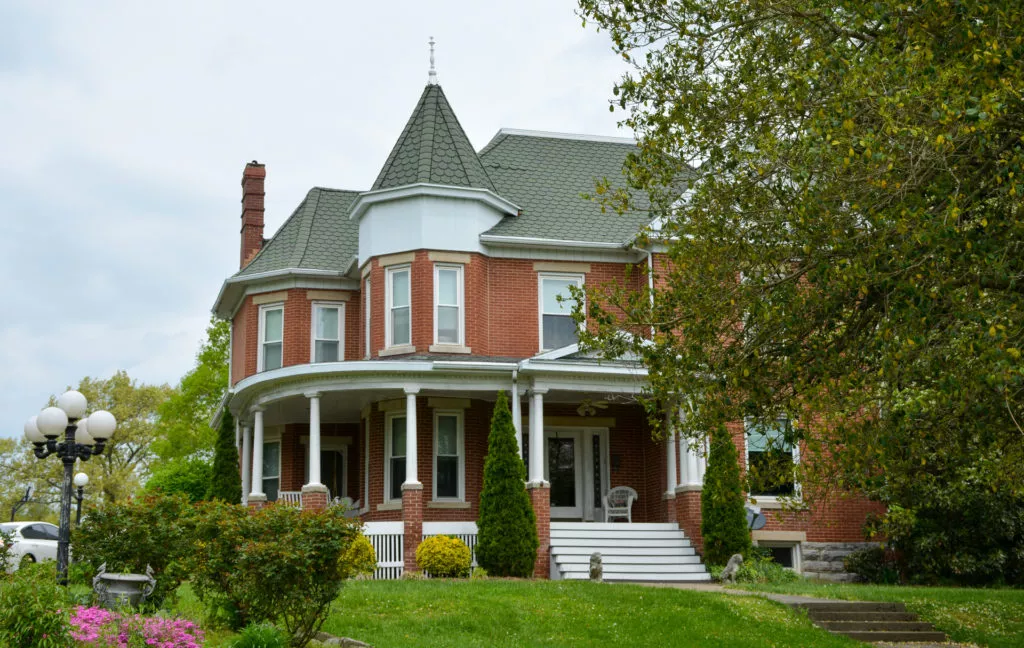 Queen Anne house exterior with tower, layered rooflines, and offset entrance